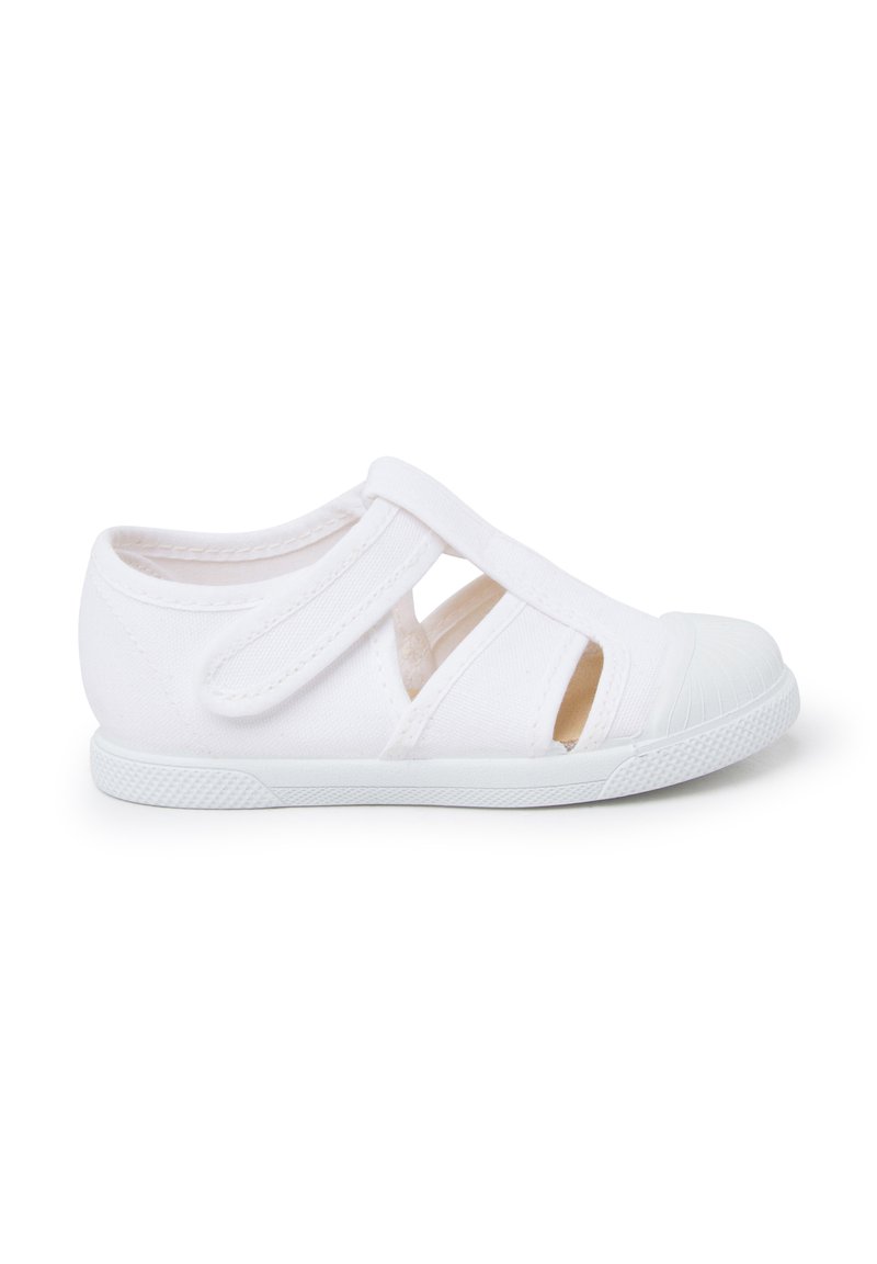 White canvas shoe with a rounded toe, Velcro straps, open sides, textured rubber sole, and minimal stitching detail.