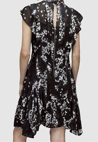 Svart klänning med vitt fjärilsmönster, genomskinligt tyg, svängda ärmar, nyckelhålsöppning bak och bakfickdragkedja. Utsvängd kjol med veck.