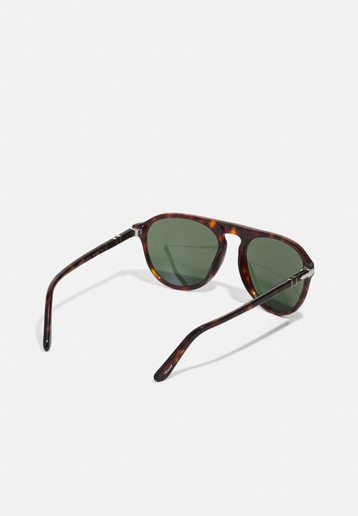 Tortoiseshell slnečné okuliare so zelenými šošovkami, okrúhly rám a kovové akcenty. Spunky majú hladký povrch, ktorý predvádza elegantný dizajn.