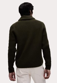 Olivgrüner, gerippter Pullover mit umschlagbarem Kragen, langen Ärmeln und enganliegendem Schnitt, aus dickem strukturierter Strickmaterial.