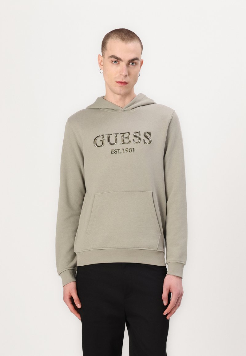 Olivgrüner Hoodie mit einer Vordertasche und einer Kapuze mit Kordelzug. Verziert mit dem "GUESS EST.1981"-Logo in dunklem Text. Lange Ärmel und strukturierten Stoff.