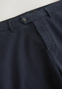 Dark blue trousers with belt loops, a buttoned waistband tab, and a hidden front zipper fly.
