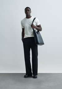 Musta nahkainen kangaskassikäsilaukku, kerma valkoinen t-paita, räätälöidyt mustat housut, yhdistetty mustiin kenkiin. Minimalistinen muotoilu, sileä pinta, istuva siluetti.