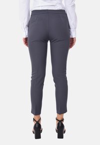 Pantaloni grigi sartoriali con una vestibilità slim, caratterizzati da una superficie liscia, tasche posteriori e una lunghezza cropped, abbinati a sandali neri con tacco a blocco.