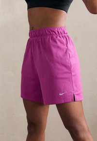 Pantaloncini sportivi rosa realizzati in tessuto leggero, con vita elastica, spacchi laterali e un piccolo logo Nike bianco sull'orlo.