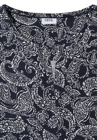 Tissu bleu marine avec motif cachemire blanc et encolure ronde avec une petite fente centrale en V, étiqueté "CECIL" au niveau du col.
