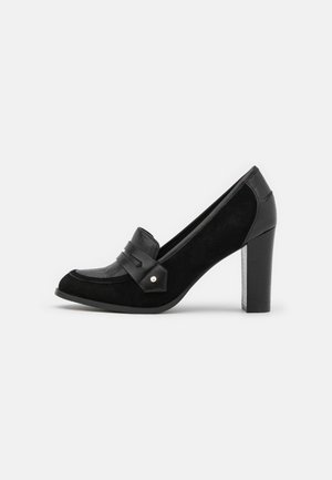 Czarny zamszowy loafer na wysokim obcasie typu słupek, z detalami ze skóry oraz ozdobnym paskiem z metalowym ćwiekiem na przodzie.