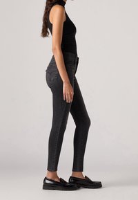 Černé zúžené džíny z denimu s hladkou strukturou, vybavené vysokým pasem, předními kapsami a klasickým designem s pěti kapsami.