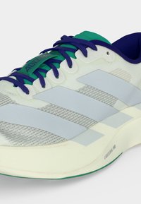 Λευκό και γκρι παπούτσι δρόμου Adidas με μπλε κορδόνια, πράσινη γλώσσα, ναυτικό γιακά και κείμενο "Lightstrike Pro" στη σόλα.