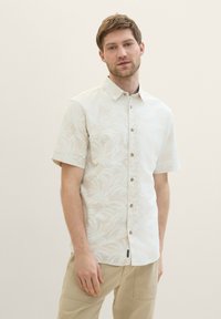 Kurzärmliges, hellbeiges Hemd mit dezentem Palmblattmuster. Verfügt über eine Knopfleiste und einen klassischen Kragen. Strukturierter Stoff.