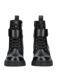 Botas de tobillo de cuero negro con detalles en tono dorado, cordones en el frente y cremallera lateral. Cuenta con una correa ancha alrededor del tobillo para mayor soporte.