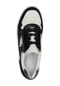 Baskets noires et crèmes présentant une combinaison de cuir et de textile, avec un système de laçage à l'avant, un détail de fermeture éclair et une semelle intérieure rembourrée.