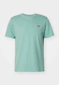 T-shirt en coton vert menthe avec des manches courtes, encolure ras du cou, et un petit logo Levi's rouge sur la poitrine. Texture lisse, coupe standard.
