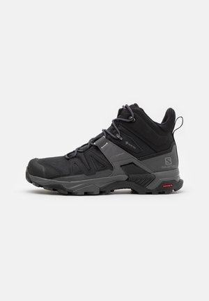 Schwarzer und grauer Salomon-Hochschnitt-Wanderschuh mit Schnürung vorne, robuster Sohle, Gore-Tex-Label und Contagrip-Logo auf der Sohle.