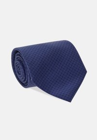 Marinblå slips med ett subtilt geometriskt mönster, prydligt rullad. Tillverkad av slät tyg med en lätt glans. Design med avsmalnande ände.