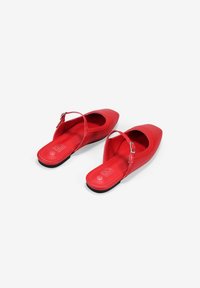 Zapatos slingback sintéticos rojos con punta afilada, con suela plana y una delgada correa en el tobillo. Textura suave sin patrones visibles.