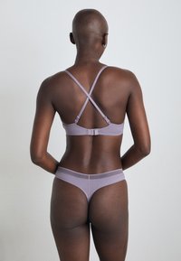 Lilla undertøysett med bh med lukking bak og kryssede stropper, samt tilhørende truse med teksturert midje. Glatt stoff, minimalistisk design.