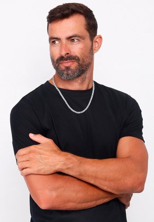 Sudraba metāla ķēdes kaklarota valkāta virs melnas īsām piedurknēm kreklam. Krekls ir ar apaļu kakla izgriezumu un brīvu piegriezumu.