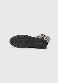Čierne šnurovacie čižmy s textúrovanou gumovou podrážkou so vzorom srdiečok a embosovaným nápisom "LOVE MOSCHINO". Zlaté kovanie.