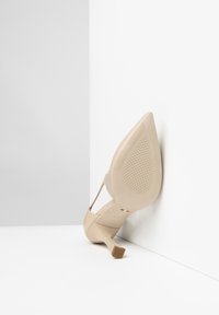 Escarpin beige à talon aigu avec un bout pointu et un talon mince et effilé. Fini en cuir verni lisse avec une semelle texturée.