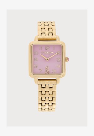 Reloj cuadrado de oro con esfera rosa, números dorados, logo de Coach New York, cinta rosa a las seis y correa de pulsera de oro enlazada.