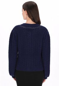 Merinovärinen neulepaita tekstuurikuvioinnilla, joustavat helma ja hihansuut. Koristeltu helmalla kaula-aukko. Lörpötyskuvio ja täyteläiset pullosolmuhihat.