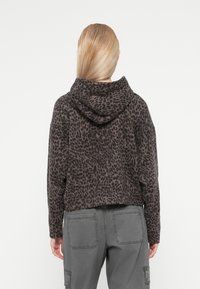 Hoodie cropped com estampa de leopardos cinza, confeccionado com um tecido texturizado e capuz. Apresenta um estilo oversized com um ajuste justo na cintura.