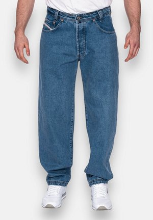 Donkerblauwe denim jeans met een losse pasvorm, voorzien van vijf zakken, koperen klinknagels en een licht vervaagde textuur. Gecombineerd met witte sneakers.