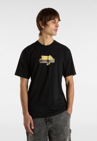 Black cotton t-shirt featuring a graphic of a yellow teddy bear on a digital clock. Short sleeves, casual fit, plain back.