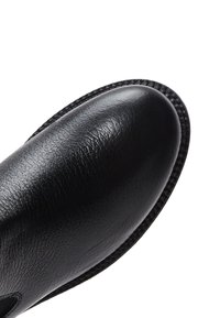 Czarne skórzane buty o gładkiej teksturze i zaokrąglonym nosku. Posiadają stębnowane wykończenie i minimalistyczny design, odpowiednie na różne okazje.
