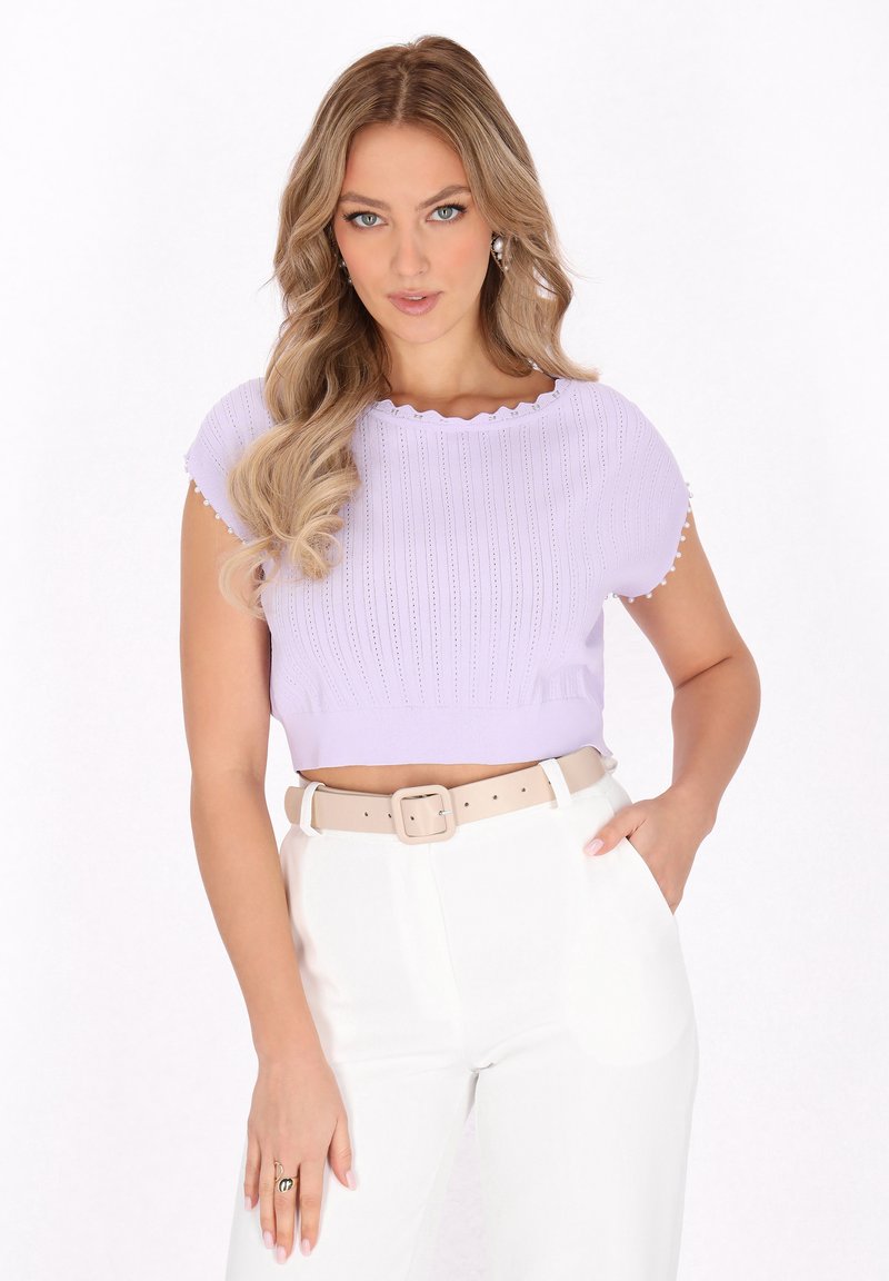 Lilla cropped top med ribbet tekstur, bølget udskæring og korte ærmer, parret med højhalsede hvide bukser og et beige bælte.