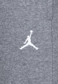 Pilkas audinys su lygiu tekstūru, centre esantis baltas Jumpman logotipas šokinėjimo pozoje.