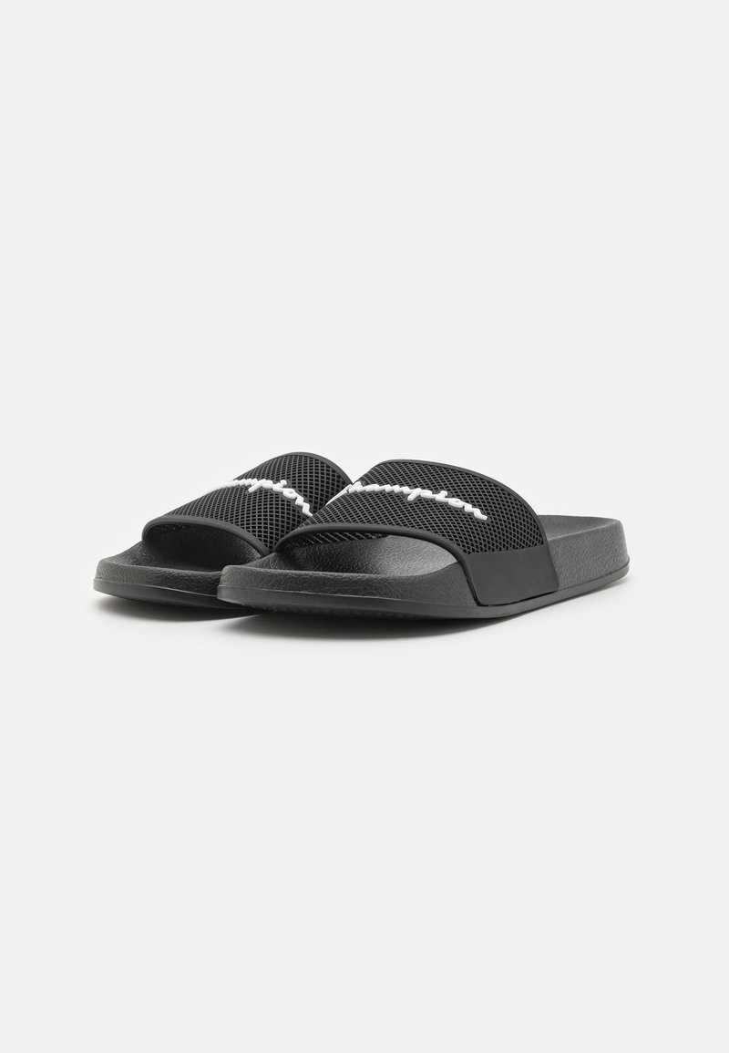 Schwarze Rutschsandalen mit einem oberen Teil aus Netzstoff, flacher Sohle und einem auffälligen weißen Markenlogo auf der Oberseite. Sie zeichnen sich durch eine glatte Textur und ein lässiges Design aus.