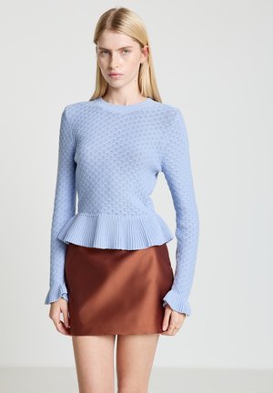 Hellblauer Strickpullover mit Schößchen-Saum und strukturiertem Muster, kombiniert mit einem braunen Satinstockrock; mit gerippten Bündchen.