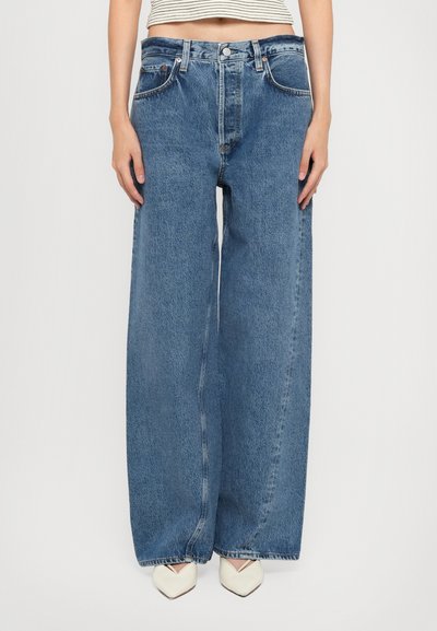 Jean large de couleur bleu clair avec une taille haute, fabriqué en denim. Comprend quatre poches et une fermeture à bouton.
