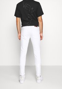 Musta, lyhythihainen t-paita, jossa on takana "NEW YORK" -teksti, yhdistettynä valkoisiin kapealahkeisiin farkkuihin ja valkoisiin lenkkareihin. Yksinkertainen ja siisti design.