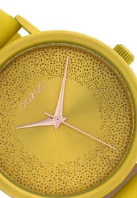 Montre jaune avec un cadran texturé arborant un contour doré et deux aiguilles en rose gold. Nom de la marque "OOZOO" intégré sur le cadran.