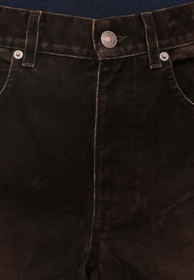Tamno smeđe traperice imaju klasičan dizajn s pet džepova, istaknutim šavovima, metalnim gumbom i suptilnom teksturiranom završnom obradom.