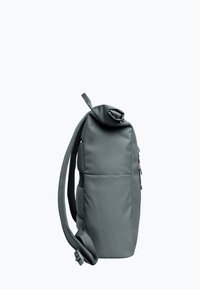 Sac à dos en tissu gris avec un design à rabat, des bretelles ajustables et des poches latérales. Texture lisse et style minimaliste.