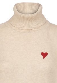 Beige Rollkragenpullover aus geripptem Strickstoff, mit einem kleinen roten Herz, das auf der linken Brustseite gestickt ist.