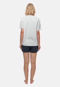 Grijze katoenen t-shirt met korte mouwen, gecombineerd met marineblauwe shorts met witte stippen, weergegeven vanaf de achterkant.