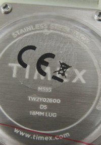 De achterkant van de kast van het roestvrijstalen horloge heeft modelnummer M555, het CE-label en de URL van de fabrikant; cirkelvormig met gegraveerde tekst.