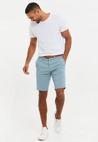 Lyseblå shorts med regular fit, lavet af bomuld, med sidelommer, parret med en hvid t-shirt med rund hals og hvide sneakers.
