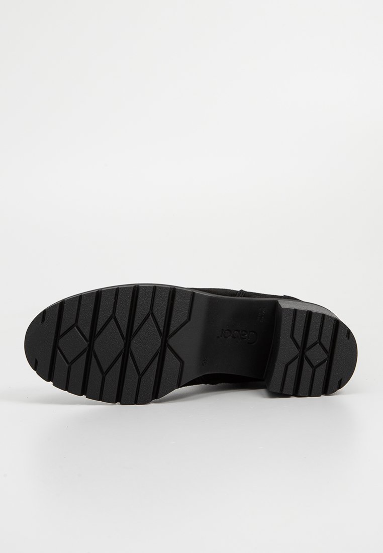 Zwarte rubberen schoenzool met een gestructureerd profiel. Heeft een platte uitstraling en een lichte kromming bij de hak. Merkl logo zichtbaar aan de zijkant.