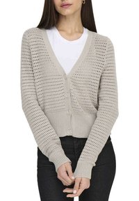Cardigan en tricot beige clair avec un col en V, un motif de tissage ouvert, trois boutons et des poignets côtelés, associé à un haut intérieur blanc.