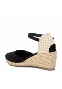 Sandalia de cuña de ante negro con suela de yute natural, detalle de tela a cuadros en el talón y correa de tobillo ajustable.