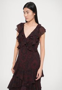 Fekete és bordó mintás ruha V-nyakkivágással, fodros ujjakkal és réteges szegéllyel. Könnyű anyag folyékony textúrával.