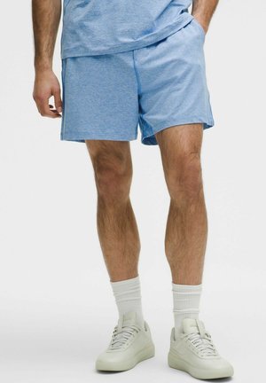 Pantalones cortos deportivos de color azul claro con una sutil textura jaspeada, bolsillos laterales y una cinturilla elástica, combinados con zapatillas claras y calcetines blancos.