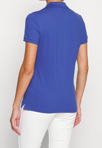 Polo de manga corta en algodón azul royal sólido, con cuello tipo polo y aberturas laterales para mayor comodidad. Diseño básico sin patrones.