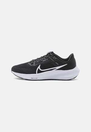 Chaussure de course Nike Pegasus 40 noire et blanche avec tige en mesh, logo swoosh blanc et semelle coussinée blanche sur fond gris clair.